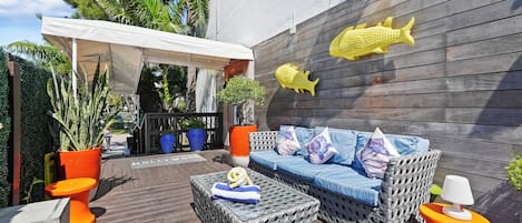 A patio area with a covered seating area, a wicker sofa, and a small table.