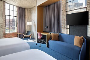 A hotel room with a large bed, a desk, a chair, a sofa, and a TV. - Aloft by Marriott Dallas Downtown (Dallas)