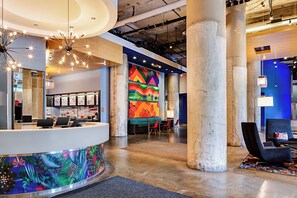 A modern lobby with a reception desk, seating area, and a colorful mural. - Aloft by Marriott Dallas Downtown (Dallas)