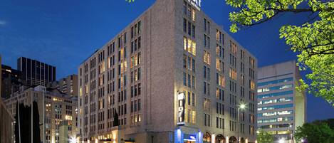 A multi-story hotel with a prominent 'Aloft' sign, featuring a classic architectural style with a flat roof and large windows.