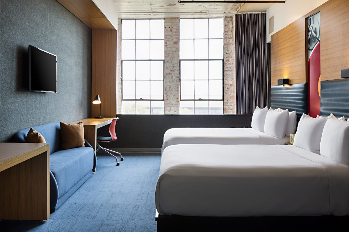A hotel room with a large bed, a sofa, a desk, and a TV mounted on the wall.