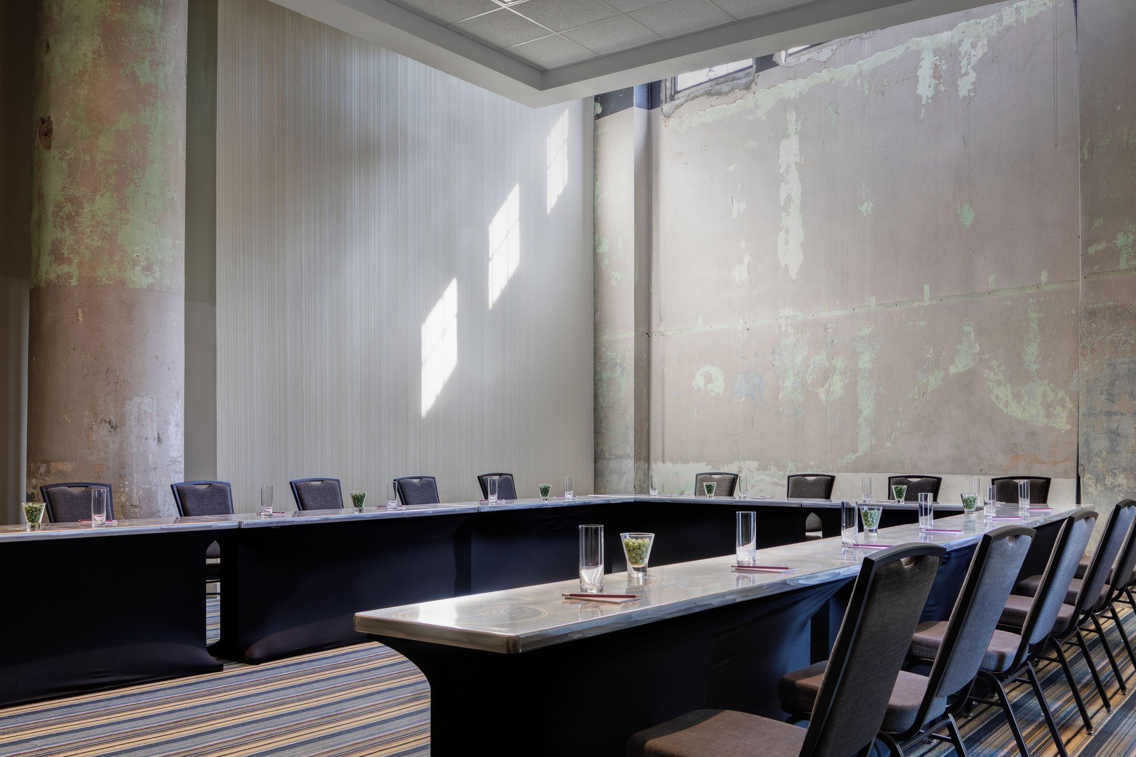 A conference room with a long table, chairs, and a patterned carpet.