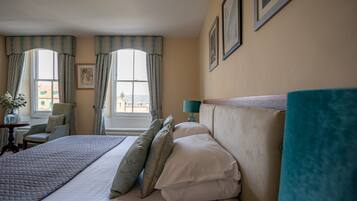 A hotel room with a bed, a chair, a table, and a window with curtains.
