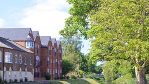 A canal with buildings on one side and a tree-lined path on the other. - Cley Hall Hotel (Spalding)