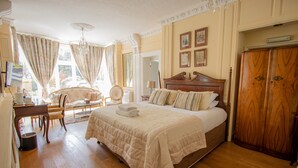 A spacious bedroom with a large bed, wooden wardrobe, and a chandelier. - Cley Hall Hotel (Spalding)
