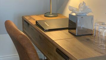 Un bureau en bois avec une lampe, une boîte de mouchoirs et un récipient en verre.