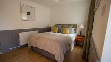 A bedroom with a bed, bedside tables, a radiator, and a framed picture on the wall.