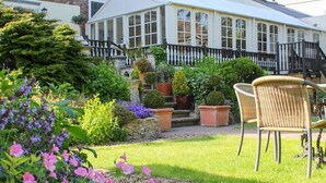 A garden with a conservatory, a staircase, and outdoor seating. - Cley Hall Hotel (Spalding)