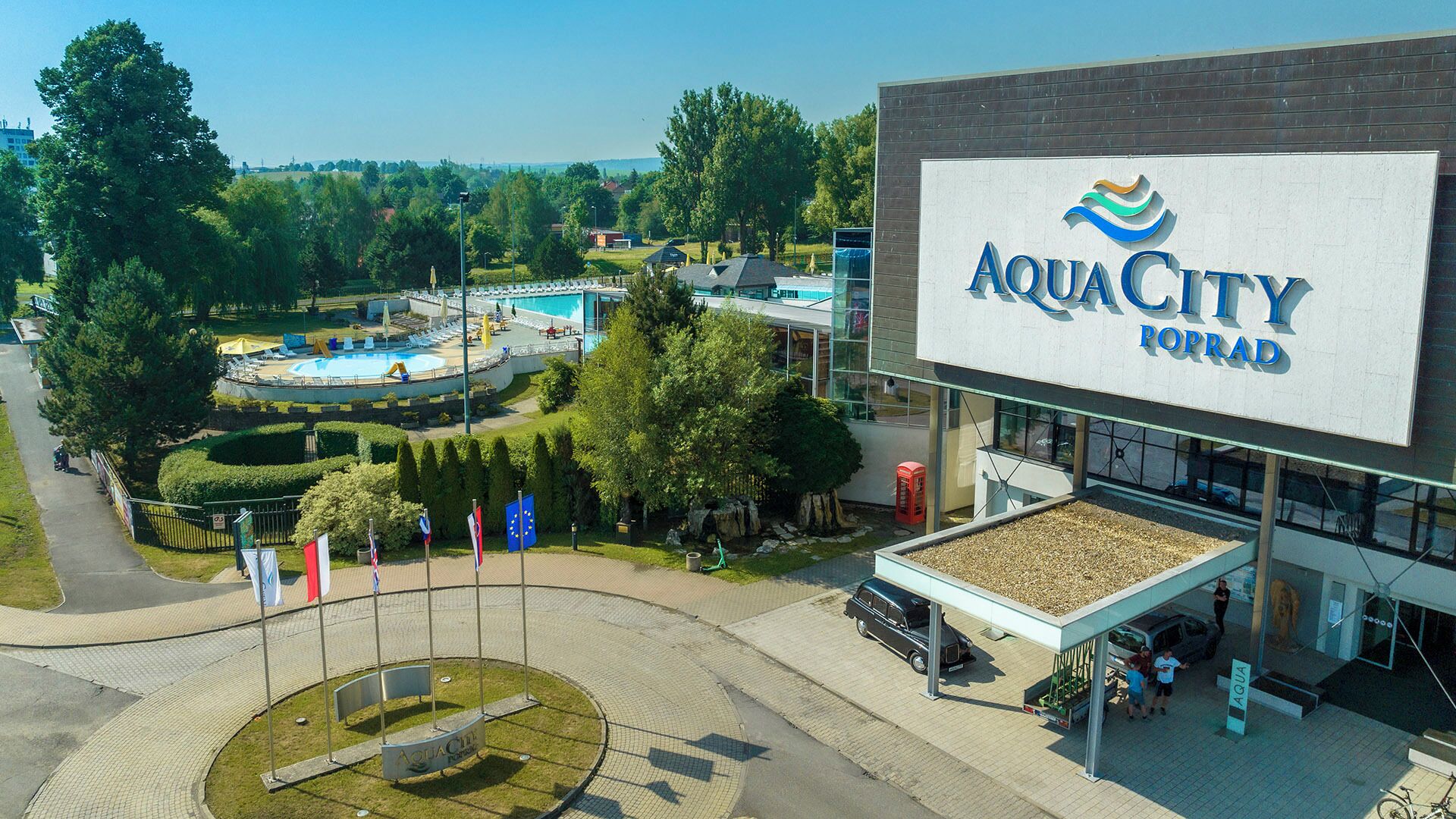 Ein großes Gebäude mit einem Schild, auf dem 'AQUACITY LORRAD' steht, und einem Schwimmbereich mit einer kreisförmigen Wasserspüle.