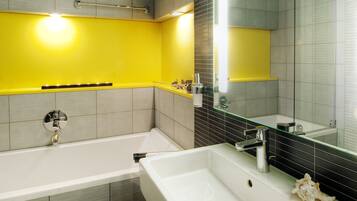 A modern bathroom with a bathtub, a sink, and a mirror.