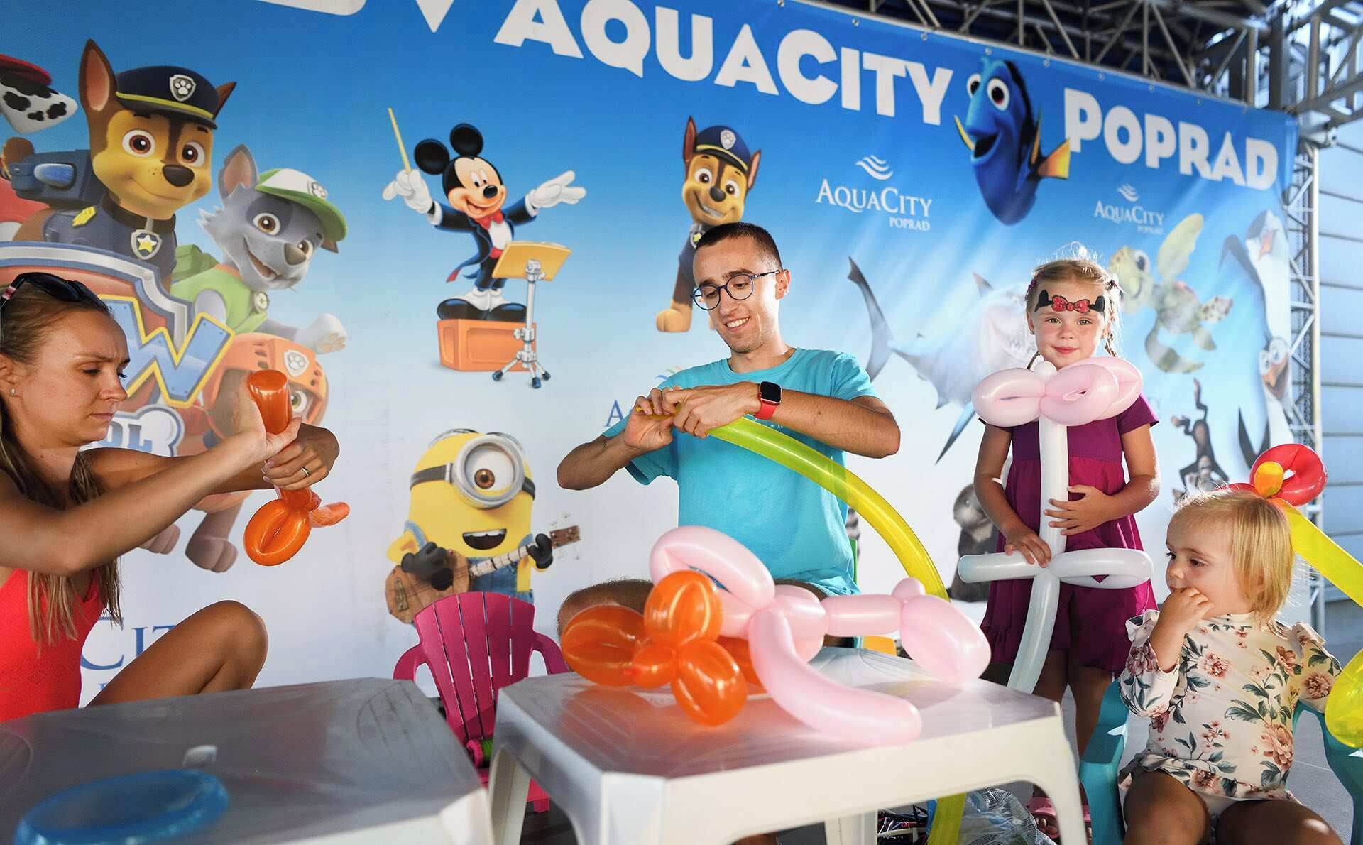 A group of people engaged in an activity with balloons and a backdrop featuring cartoon characters.