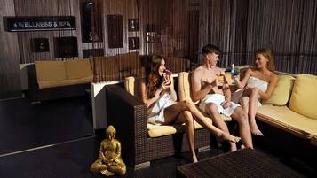 Un espacio de bienestar con un sofá y sillones, una estatua de Buda y un cartel que indica servicios de bienestar y spa.