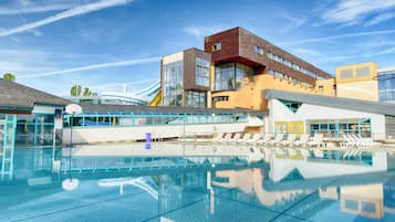 A swimming pool with clear blue water, surrounded by modern buildings with large windows and a slide.