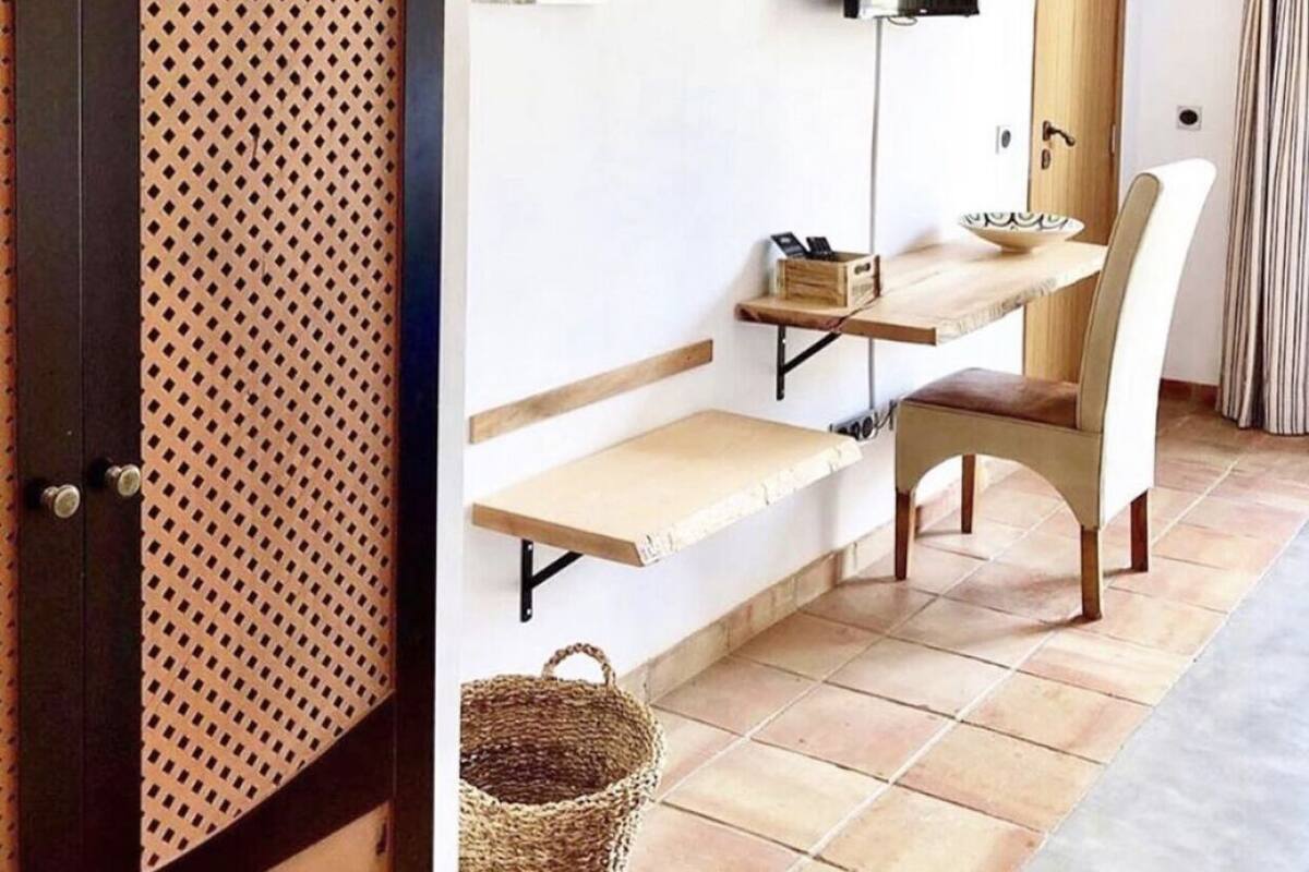 A room with a wooden bench, a chair, a television, and a wall-mounted shelf.