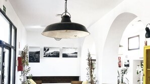 Amplia sala de estar con techo alto, una lámpara colgante grande, chimenea y una mesa de comedor con plantas en macetas.