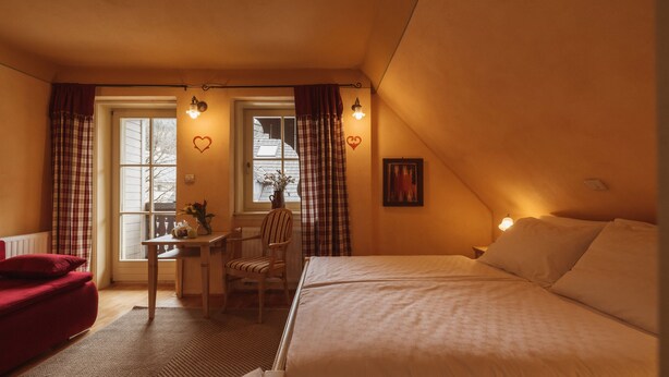 A cozy bedroom with a bed, a chair, a small table, and a window with curtains. - Vitranc (Kranjska Gora)