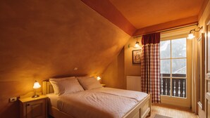 A cozy bedroom with a single bed, a nightstand with a lamp, a window with a view of a balcony, and a radiator. - Vitranc (Kranjska Gora)