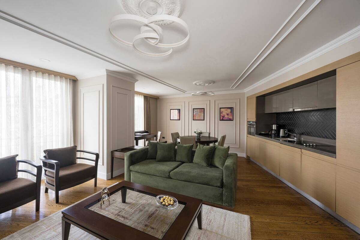 Un salon moderne avec un canapé vert, une table basse en bois et un coin repas comprenant une table et des chaises.