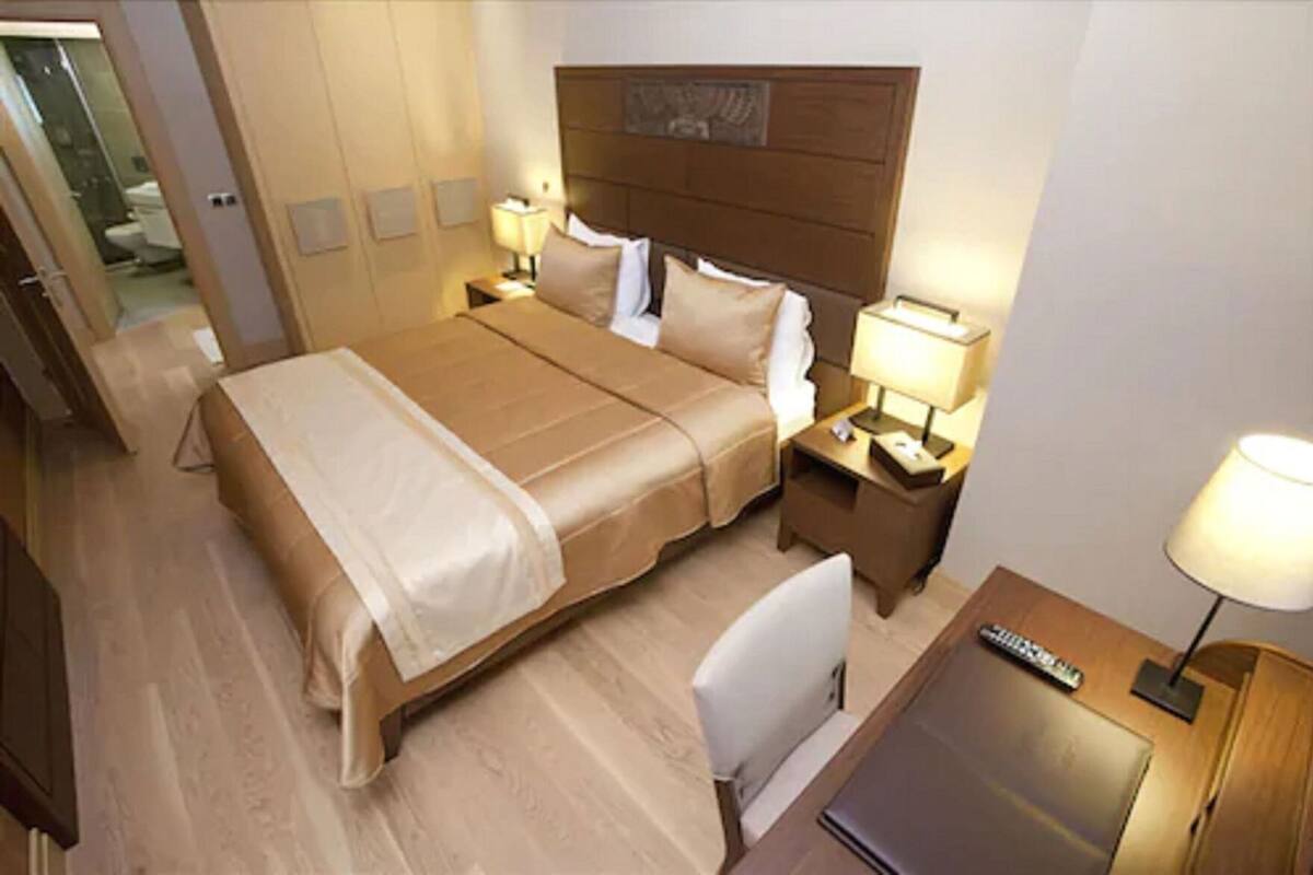 Une chambre d’hôtel avec un lit double, deux tables de chevet avec des lampes, un bureau avec une chaise et un petit réfrigérateur.