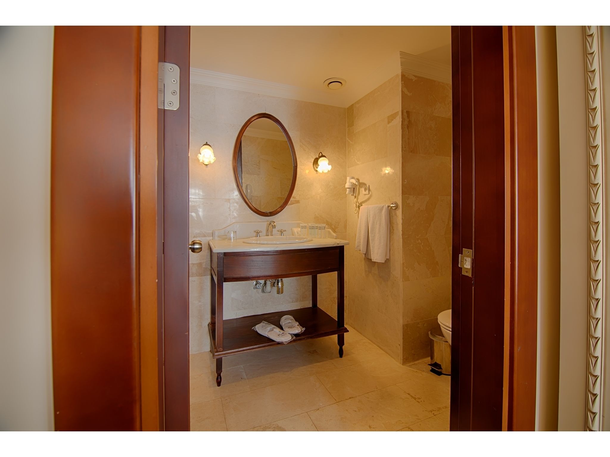 A bathroom with a wooden vanity, a large mirror, a sink, and a toilet.