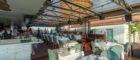 Un restaurante con terraza, zona de bar y vistas a un edificio histórico.