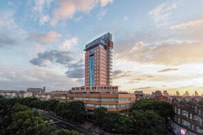 A high-rise hotel with multiple floors, surrounded by trees and other buildings.