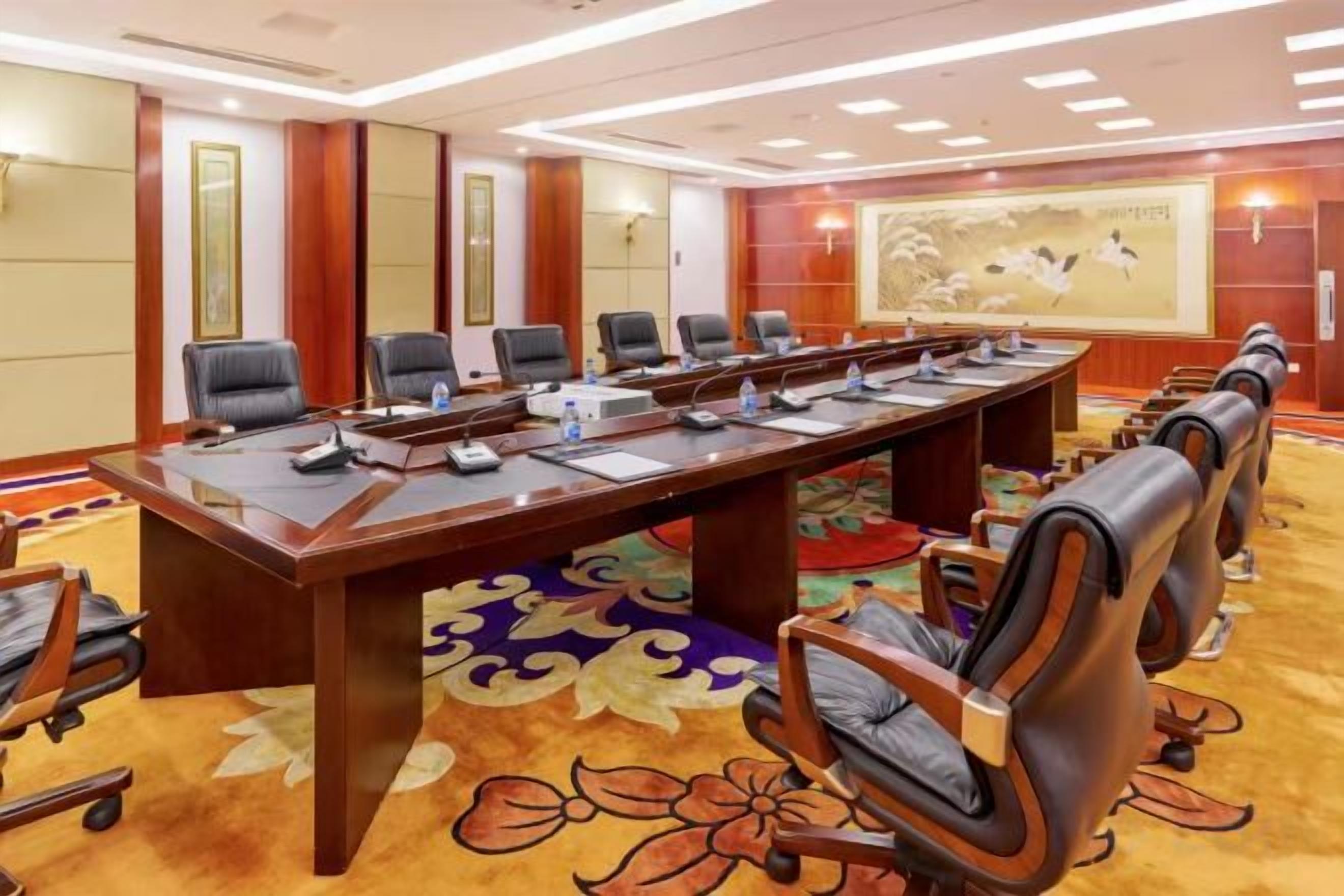 A conference room with a long table, multiple chairs, and a carpeted floor.