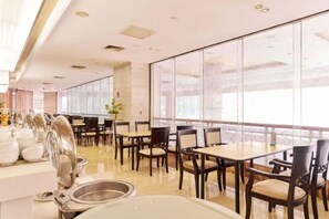 Een restaurant met tafels, stoelen, een buffetgedeelte en grote ramen.