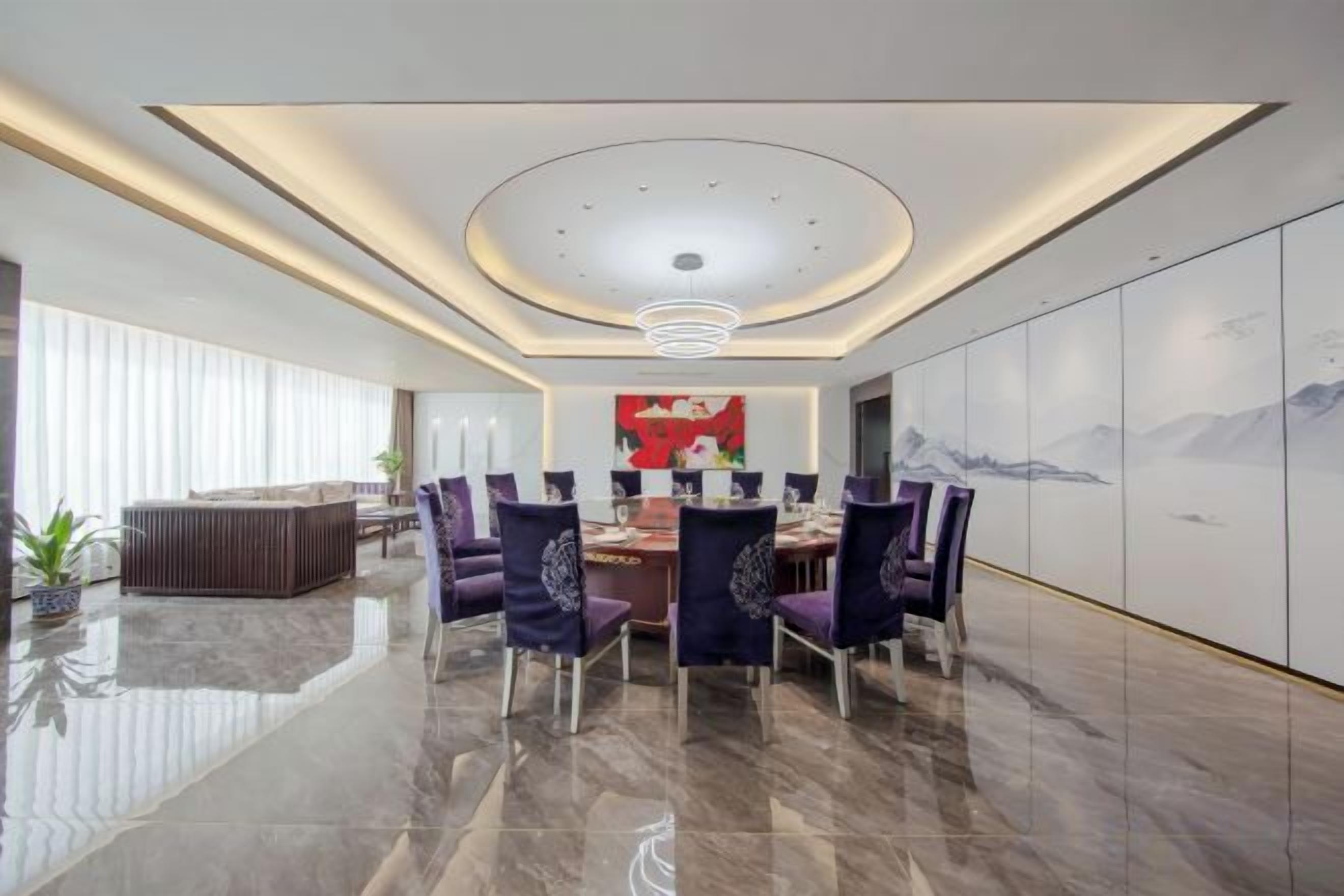 A modern dining area with a round table, chairs, and a ceiling light fixture.