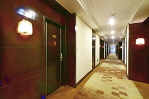 Un pasillo de hotel con piso alfombrado, puertas e iluminación empotrada en la pared.