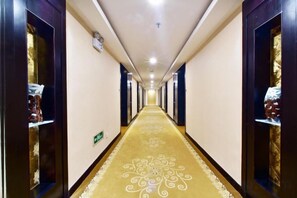 A hotel hallway with a carpeted floor, doors on both sides, and a light fixture on the ceiling. - Jiangyin Life Island Hotel (Wuxi)