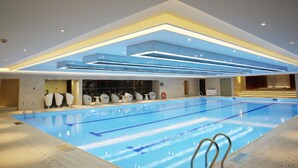 A modern indoor swimming pool with clear lane markings, a seating area with chairs, and a reception desk. - Shantou International Hotel (Shantou)