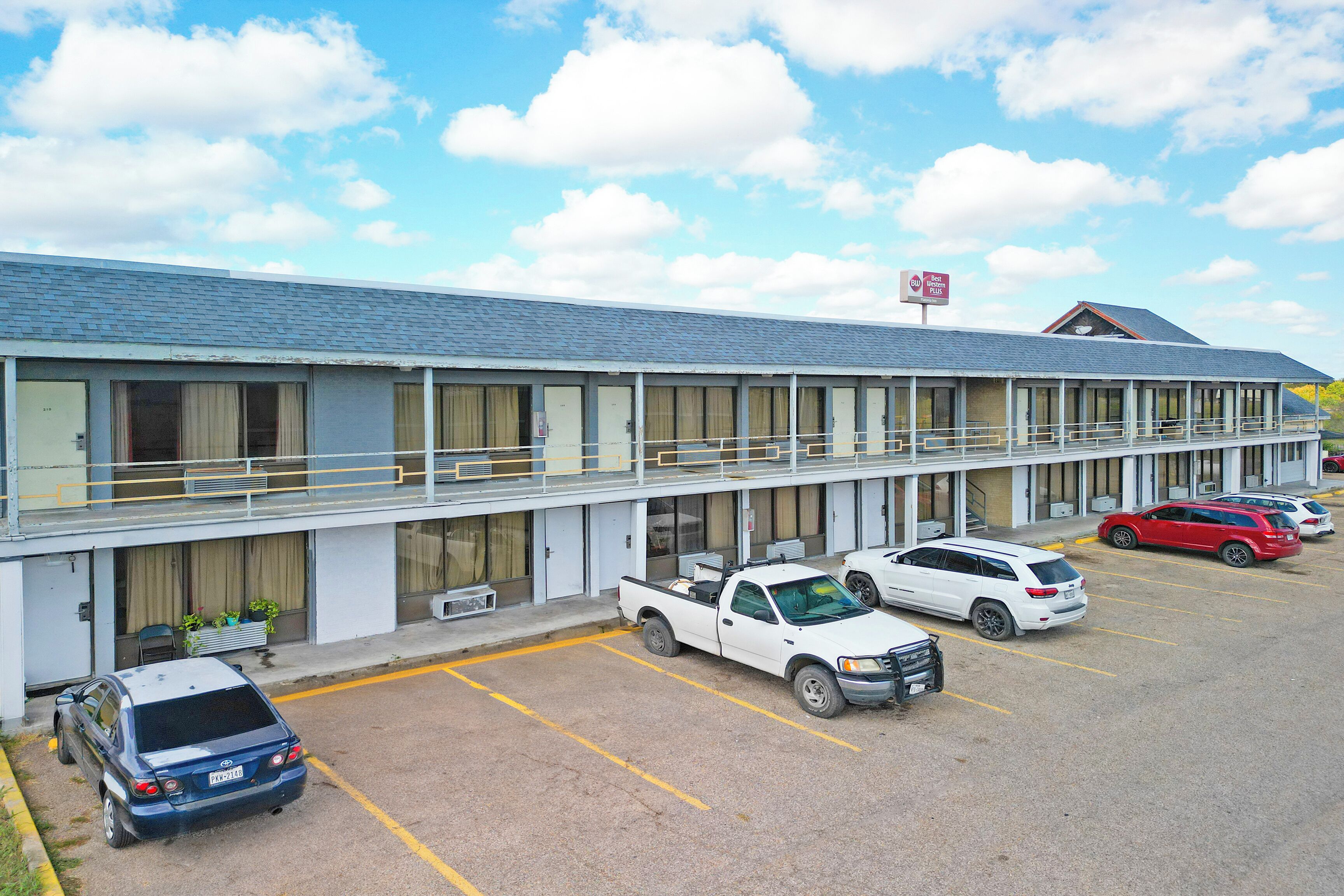 Un motel con parcheggio, una tettoia e diverse auto parcheggiate.