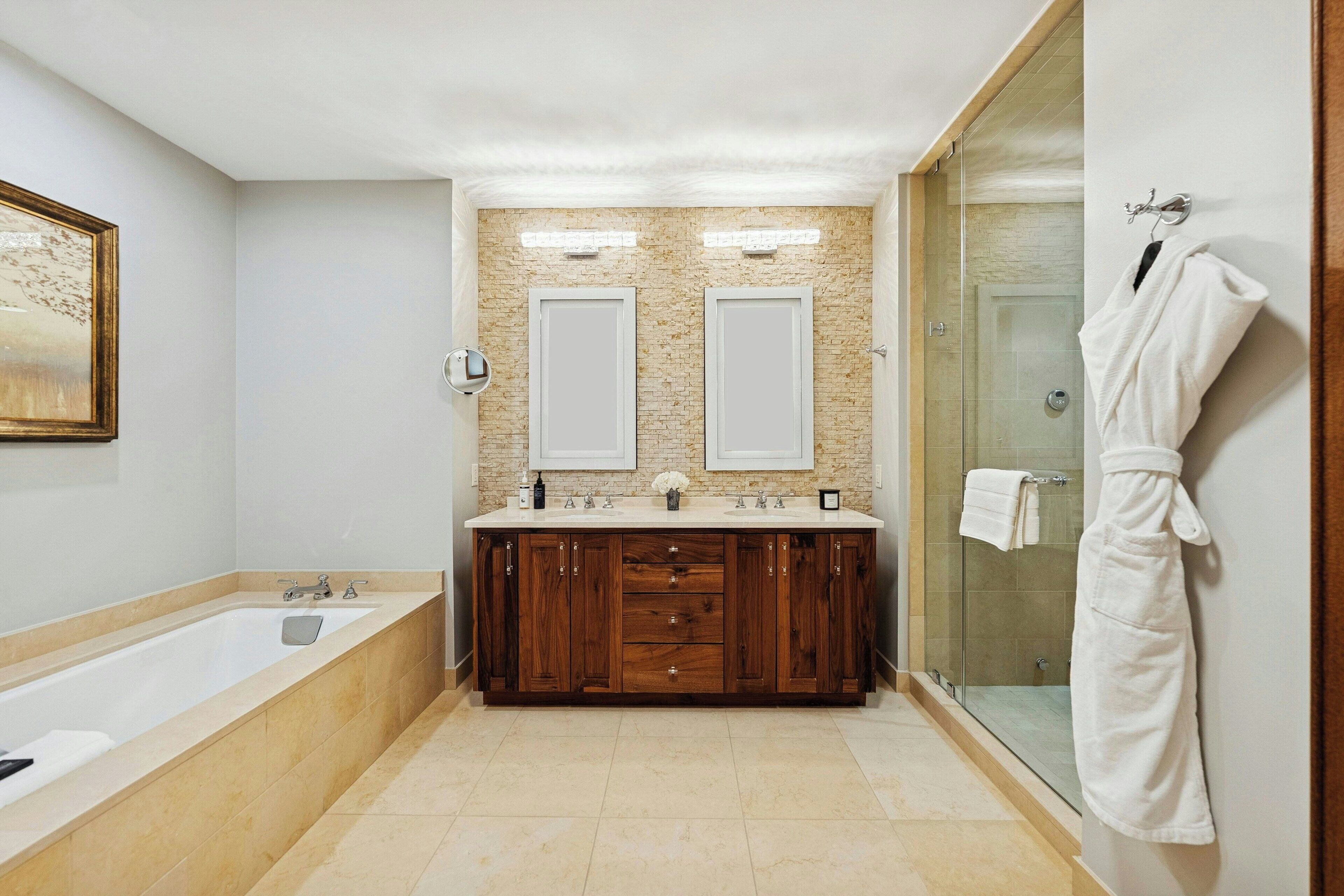 A modern bathroom with a large bathtub, double sinks, and a glass shower enclosure.