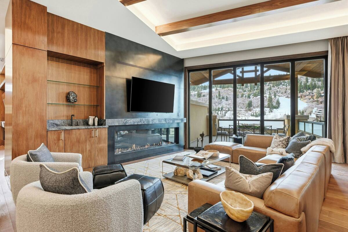 A modern living room with a fireplace, comfortable seating, and a large window offering a scenic view.