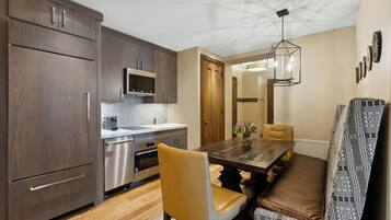 A modern kitchen with dark wood cabinets, stainless steel appliances, and a wooden dining table with a bench.