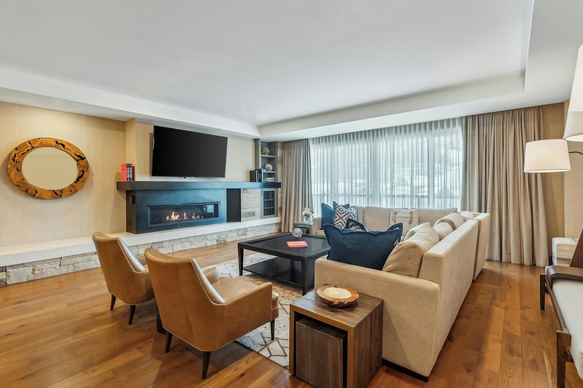 A modern living room with a fireplace, leather furniture, and a large TV.