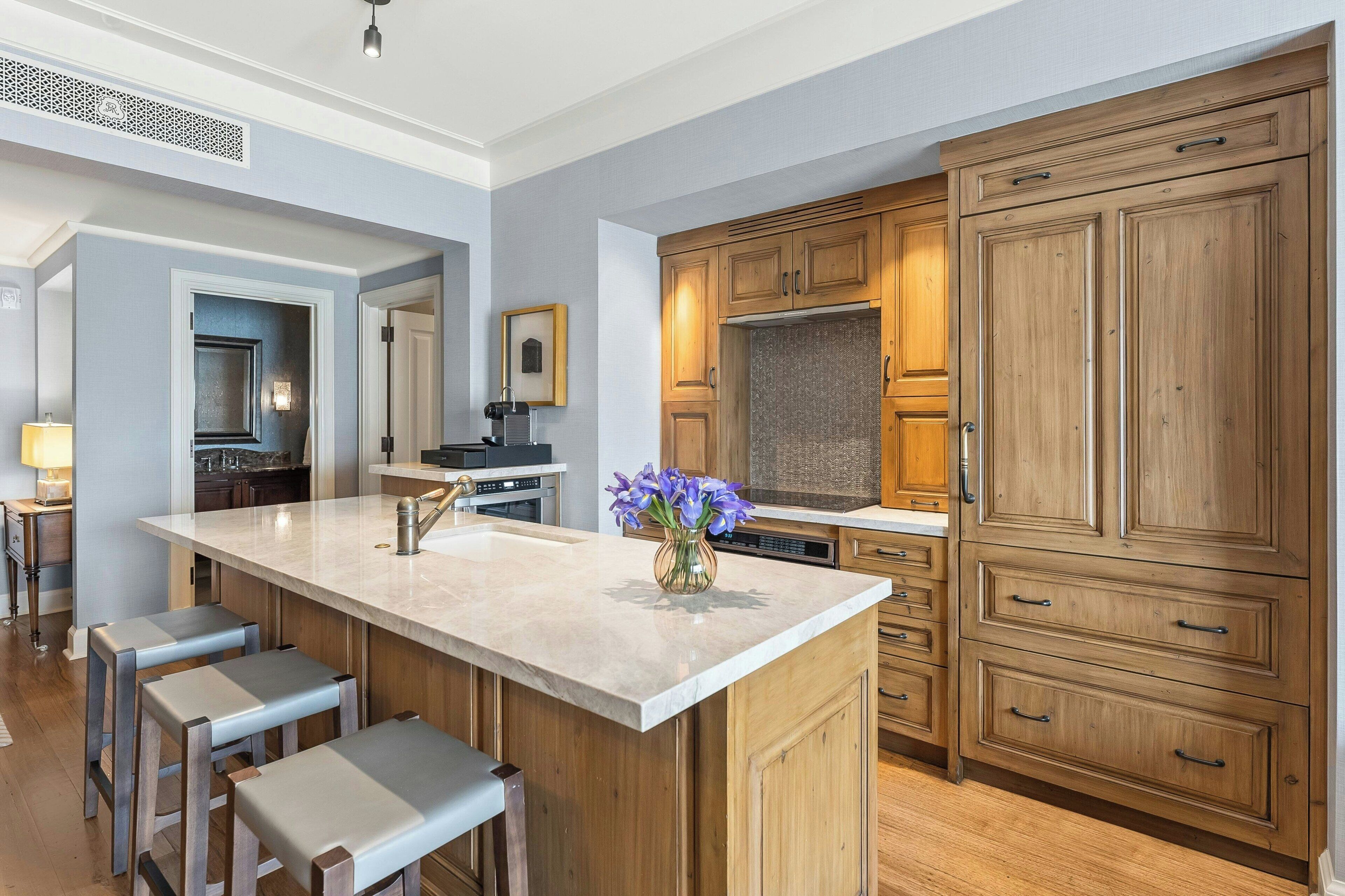 Una cucina moderna con un'isola grande, mobili in legno e sgabelli da bar.