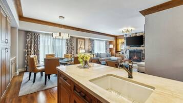A modern kitchen with a large island, wooden cabinets, and a stone fireplace.