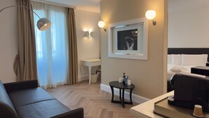 Una habitación de hotel con cama, escritorio, silla, mesita y cafetera.