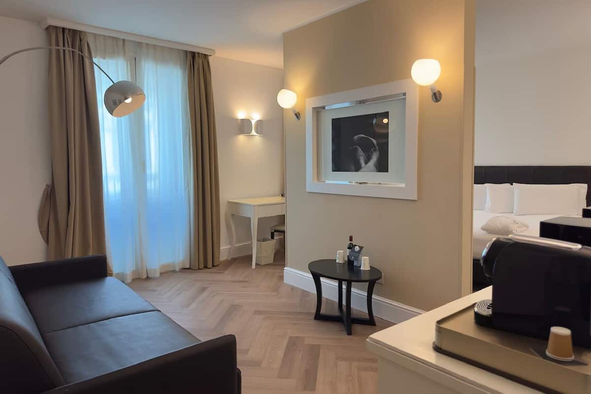 Une chambre d’hôtel équipée d’un lit, d’un bureau, d’une chaise, d’une petite table et d’une machine à café.