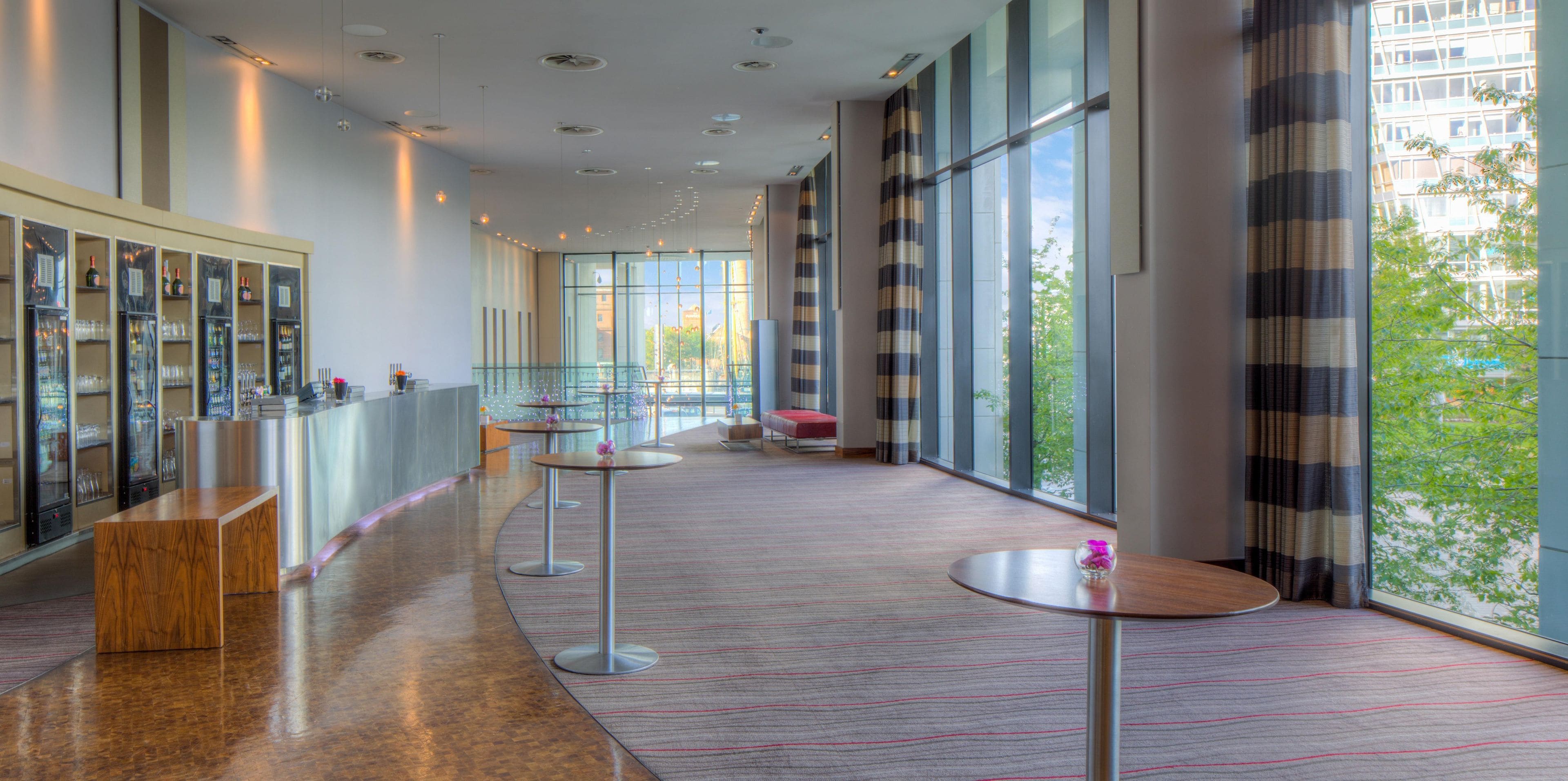 En hotelllobby med en lång korridor, en receptionsdisk och en sittgrupp med runda bord.