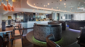 A modern bar area with a circular seating arrangement, a bar counter, and overhead lighting. - Hilton Liverpool City Centre (Liverpool)
