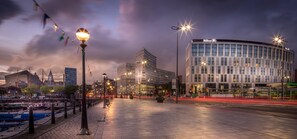 A modern building with a curved facade and the Hilton logo, surrounded by a well-lit urban street at dusk. - Hilton Liverpool City Centre (Liverpool)