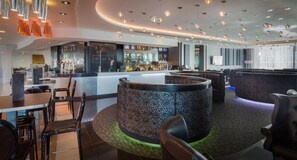 A modern bar area with a circular seating arrangement, a bar counter, and overhead lighting.