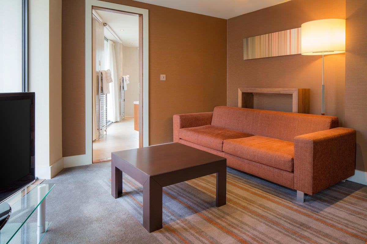 Un salon moderne avec un canapé, une table basse, un téléviseur à écran plat et une lampe.