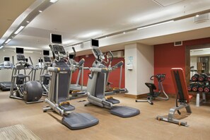 Una palestra con diverse macchine per esercizi, tra cui tapis roulant ed ellittiche, disposte in un ambiente ampio.