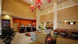 A spacious lobby with a reception desk, seating area, and a large potted plant.