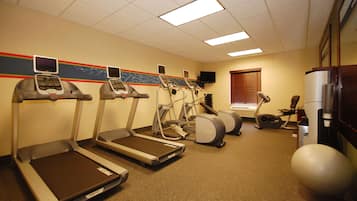 A fitness room with treadmills, an elliptical, a stationary bike, and a large exercise ball.