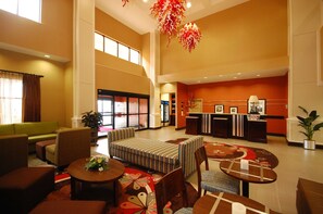 A spacious lobby with a reception desk, seating area, and large windows.